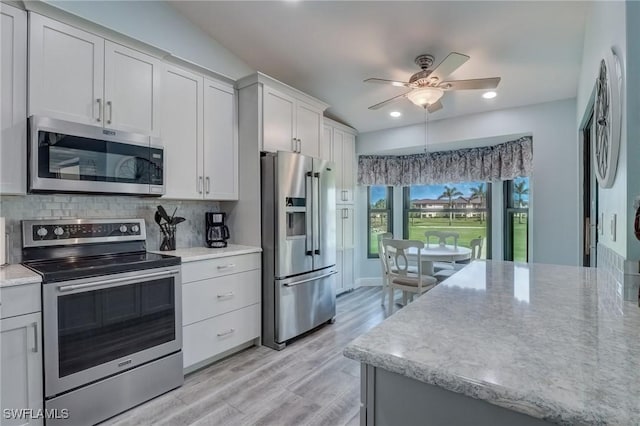 12170 Kelly Greens Blvd Unit 88, Fort Myers, FL 33908 - kitchen with stainless steel appliances, light wood-style floors, ceiling fan, tasteful backsplash, and white cabinets