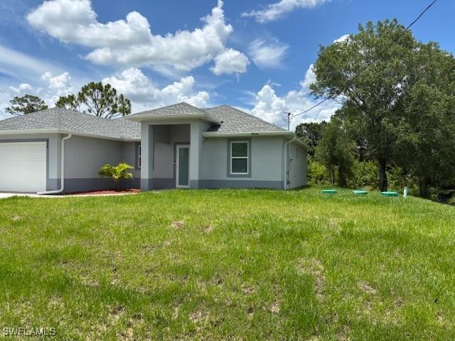 406 W 15th St, Lehigh Acres, FL 33972 - view of front of house with stucco siding, an attached garage, and a front yard