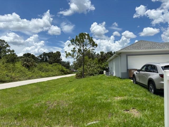 406 W 15th St, Lehigh Acres, FL 33972 - view of green lawn with a garage