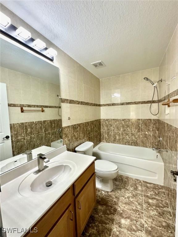 12505 Mcgregor Blvd Unit 204B, Fort Myers, FL 33919 - bathroom featuring tile walls, vanity, shower / washtub combination, and a textured ceiling