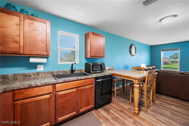 1100 NW 20th St, Cape Coral, FL 33993 - kitchen with black dishwasher, stainless steel microwave, light wood-style floors, open floor plan, and brown cabinetry
