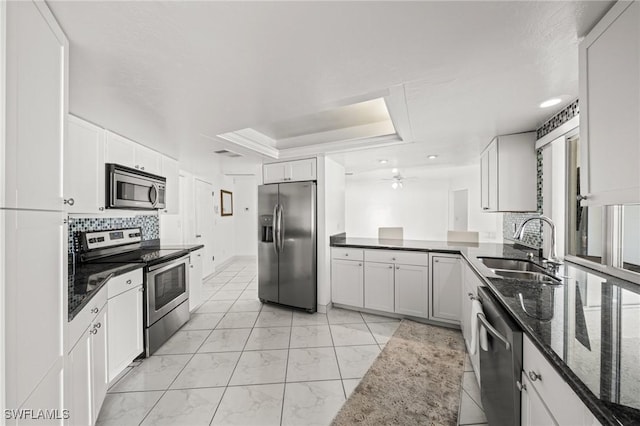 1442 Wellington Ct, Cape Coral, FL 33904 - kitchen with stainless steel appliances, a raised ceiling, decorative backsplash, light marble finish floors, and dark stone countertops