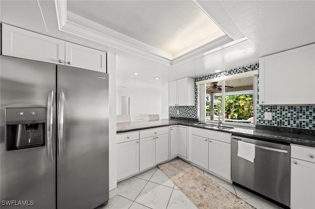 1442 Wellington Ct, Cape Coral, FL 33904 - kitchen with appliances with stainless steel finishes, a tray ceiling, white cabinetry, light marble finish flooring, and tasteful backsplash