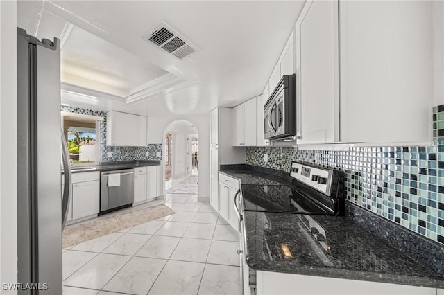1442 Wellington Ct, Cape Coral, FL 33904 - kitchen featuring appliances with stainless steel finishes, arched walkways, white cabinets, decorative backsplash, and a raised ceiling