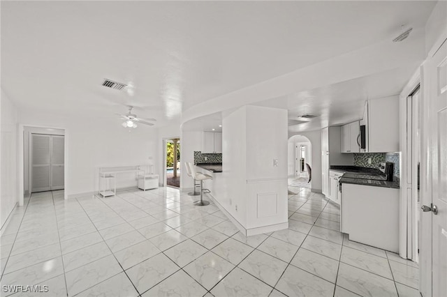 1442 Wellington Ct, Cape Coral, FL 33904 - kitchen with dark countertops, arched walkways, backsplash, and a ceiling fan