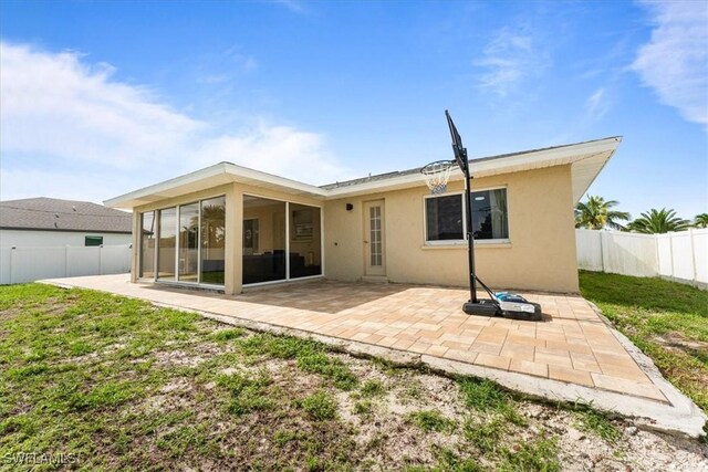 605 SW 18th Ter, Cape Coral, FL 33991 - back of property with stucco siding, a fenced backyard, a sunroom, and a patio area
