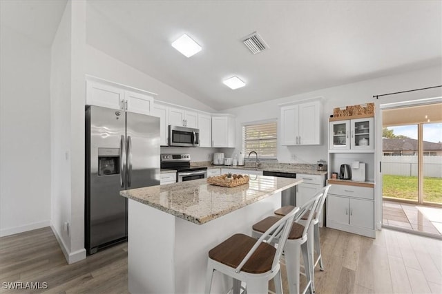 605 SW 18th Ter, Cape Coral, FL 33991 - kitchen featuring stainless steel appliances, lofted ceiling, white cabinetry, plenty of natural light, and light wood-style floors