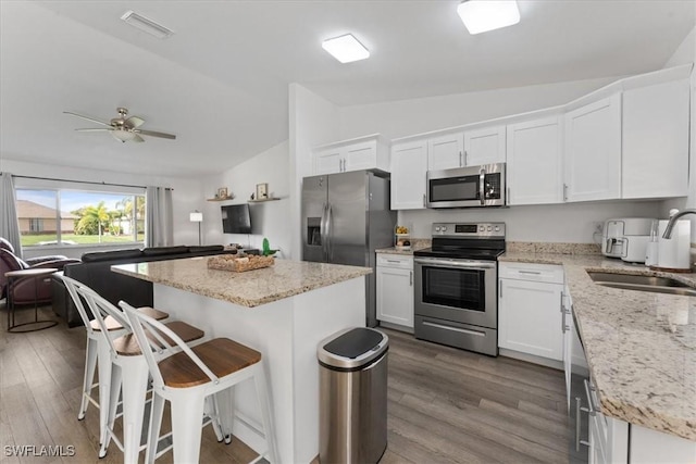 605 SW 18th Ter, Cape Coral, FL 33991 - kitchen with appliances with stainless steel finishes, lofted ceiling, white cabinetry, dark wood finished floors, and a kitchen island
