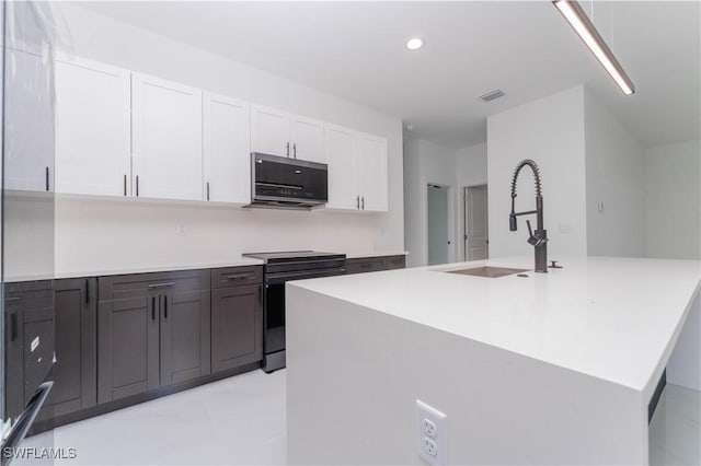 615 Greenbriar Blvd, Lehigh Acres, FL 33972 - kitchen with black electric range, white cabinets, light countertops, recessed lighting, and a kitchen island with sink