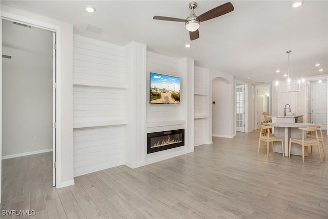14671 Edgewater Cir, Naples, FL 34114 - living area with ceiling fan, arched walkways, light wood-style floors, recessed lighting, and a glass covered fireplace