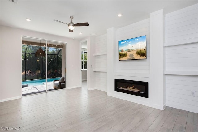14671 Edgewater Cir, Naples, FL 34114 - unfurnished living room with a ceiling fan, wood finished floors, a glass covered fireplace, and recessed lighting