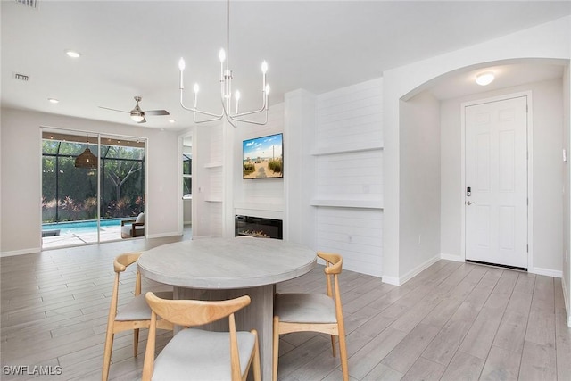 14671 Edgewater Cir, Naples, FL 34114 - dining room with arched walkways, light wood-style floors, a glass covered fireplace, ceiling fan, and recessed lighting
