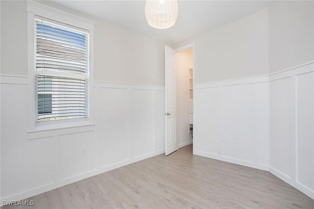 14671 Edgewater Cir, Naples, FL 34114 - empty room featuring a decorative wall, wood finished floors, healthy amount of natural light, and a wainscoted wall