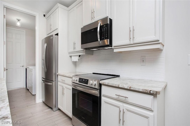 14671 Edgewater Cir, Naples, FL 34114 - kitchen with stainless steel appliances, separate washer and dryer, decorative backsplash, white cabinets, and light wood-type flooring