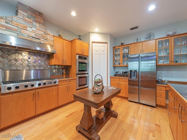21950 N River Rd, Alva, FL 33920 - kitchen featuring stainless steel appliances, light wood-style floors, decorative backsplash, glass insert cabinets, and recessed lighting