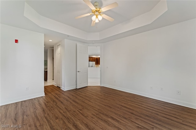 15250 Riverbend Blvd Unit 101, North Fort Myers, FL 33917 - unfurnished room with dark wood-style floors, a tray ceiling, and ceiling fan