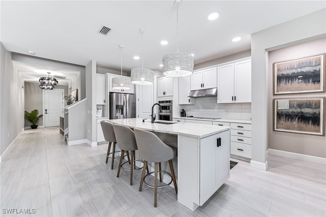 19604 Beechcrest Pl, Estero, FL 33928 - kitchen with appliances with stainless steel finishes, under cabinet range hood, a chandelier, a center island with sink, and recessed lighting