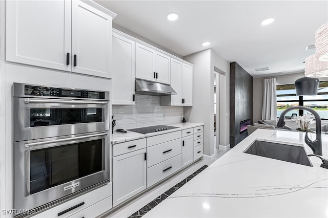 19604 Beechcrest Pl, Estero, FL 33928 - kitchen featuring double oven, black electric cooktop, under cabinet range hood, recessed lighting, and inlaid floor details