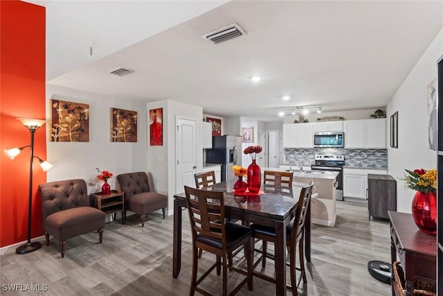 9059 Aegean Cir, Lehigh Acres, FL 33936 - dining room with light wood-style floors and rail lighting