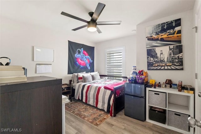 9059 Aegean Cir, Lehigh Acres, FL 33936 - bedroom with freestanding refrigerator, light wood-type flooring, and a ceiling fan