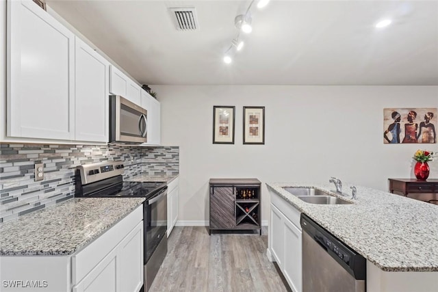 9059 Aegean Cir, Lehigh Acres, FL 33936 - kitchen with appliances with stainless steel finishes, light wood finished floors, tasteful backsplash, white cabinetry, and light stone counters
