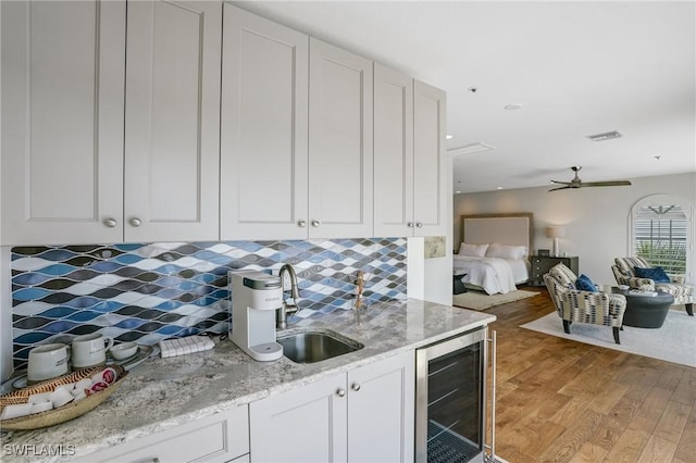 4031 Bayside Rd, Fort Myers Beach, FL 33931 - kitchen with beverage cooler, light wood-style floors, backsplash, and white cabinets