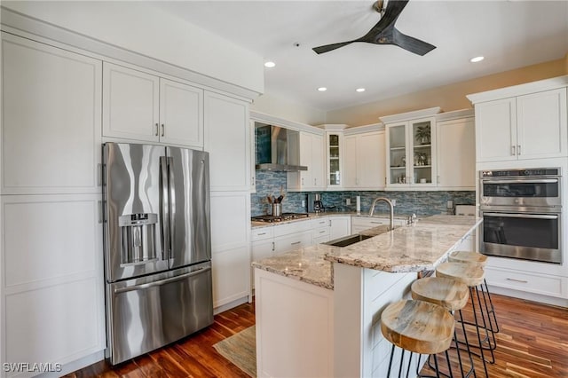 4031 Bayside Rd, Fort Myers Beach, FL 33931 - kitchen featuring appliances with stainless steel finishes, wall chimney range hood, dark wood-style floors, decorative backsplash, and ceiling fan