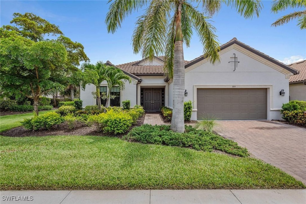 3253 Quilcene Ln, Naples, FL 34114 - mediterranean / spanish home with stucco siding, an attached garage, a front yard, and driveway