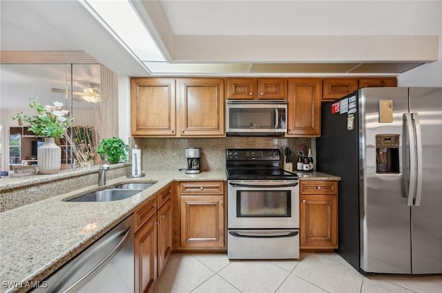13090 Amberley Ct Unit 1103, Bonita Springs, FL 34135 - kitchen featuring appliances with stainless steel finishes, brown cabinets, light tile patterned floors, light stone counters, and backsplash