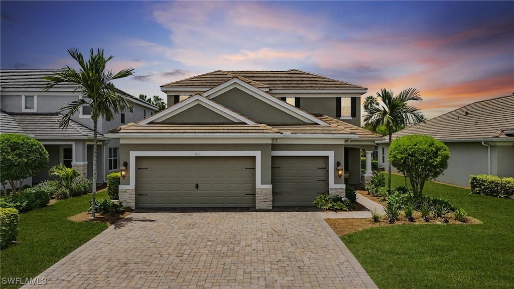 4276 Watercolor Way, Fort Myers, FL 33966 - view of front of property with stucco siding, decorative driveway, stone siding, a yard, and a garage