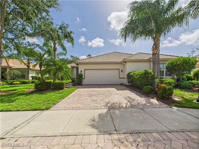 11217 Suffield St, Fort Myers, FL 33913 - view of front of property featuring a tile roof, stucco siding, decorative driveway, an attached garage, and a front lawn