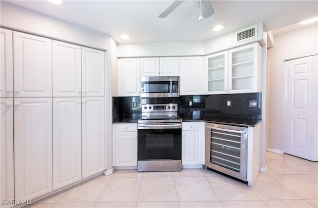 12330 Notting Hill Ln Unit 14, Bonita Springs, FL 34135 - kitchen with appliances with stainless steel finishes, beverage cooler, light tile patterned flooring, white cabinetry, and backsplash