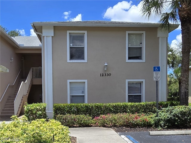 12330 Notting Hill Ln Unit 14, Bonita Springs, FL 34135 - view of home's exterior with stucco siding, uncovered parking, and stairs