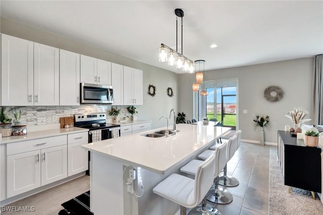 43837 Cattleman Dr, Punta Gorda, FL 33982 - kitchen featuring stainless steel appliances, tasteful backsplash, light countertops, white cabinetry, and an island with sink