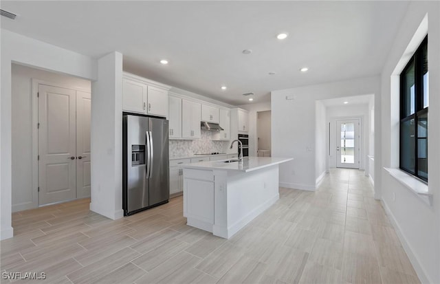 6144 Liberty St, Ave Maria, FL 34142 - kitchen with stainless steel refrigerator with ice dispenser, under cabinet range hood, an island with sink, backsplash, and light countertops