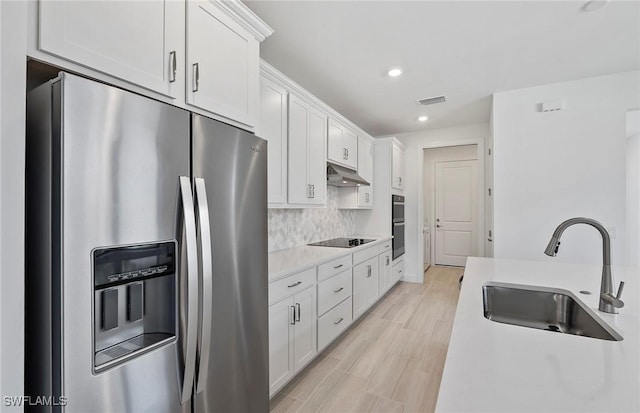 6144 Liberty St, Ave Maria, FL 34142 - kitchen featuring stainless steel appliances, under cabinet range hood, white cabinets, recessed lighting, and tasteful backsplash