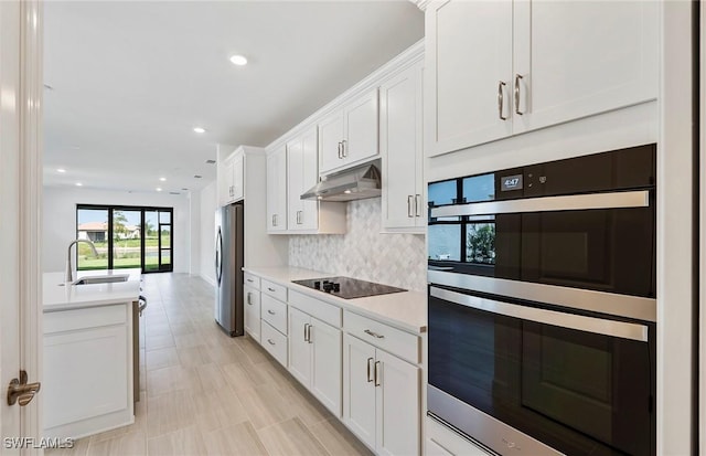 6144 Liberty St, Ave Maria, FL 34142 - kitchen featuring appliances with stainless steel finishes, under cabinet range hood, light countertops, white cabinetry, and backsplash