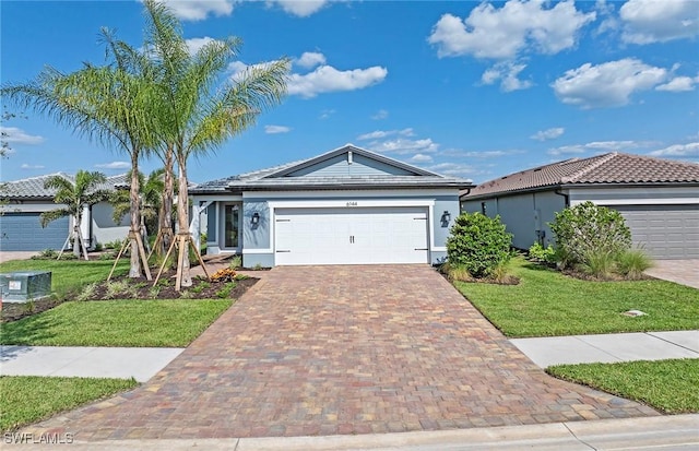 6144 Liberty St, Ave Maria, FL 34142 - ranch-style home with a garage, a front yard, decorative driveway, and stucco siding
