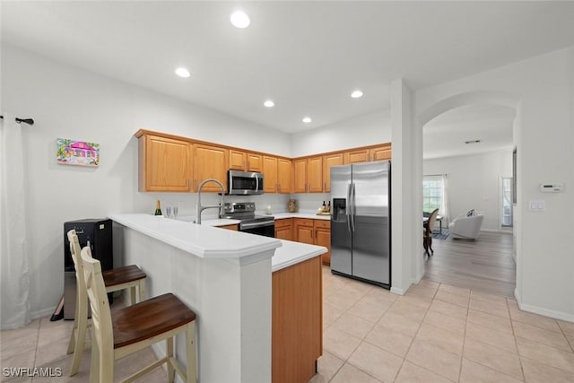 9795 Gladiolus Bulb Loop, Fort Myers, FL 33908 - kitchen featuring appliances with stainless steel finishes, arched walkways, a peninsula, a breakfast bar area, and light countertops