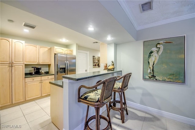 225 SW 43rd Ln, Cape Coral, FL 33914 - kitchen with stainless steel fridge with ice dispenser, light brown cabinetry, a breakfast bar, light tile patterned flooring, and crown molding