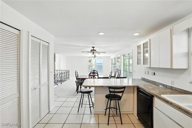 131 Bay Mar Dr, Fort Myers Beach, FL 33931 - kitchen with black dishwasher, a peninsula, white cabinetry, light tile patterned flooring, and glass insert cabinets