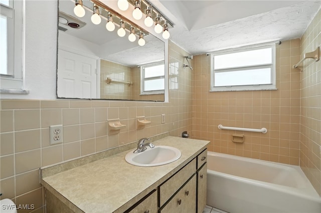 131 Bay Mar Dr, Fort Myers Beach, FL 33931 - bathroom featuring tile walls, shower / bathtub combination, vanity, and healthy amount of natural light