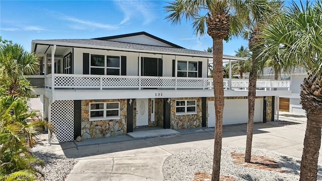 131 Bay Mar Dr, Fort Myers Beach, FL 33931 - view of front of property featuring driveway, a sunroom, a garage, a shingled roof, and stone siding