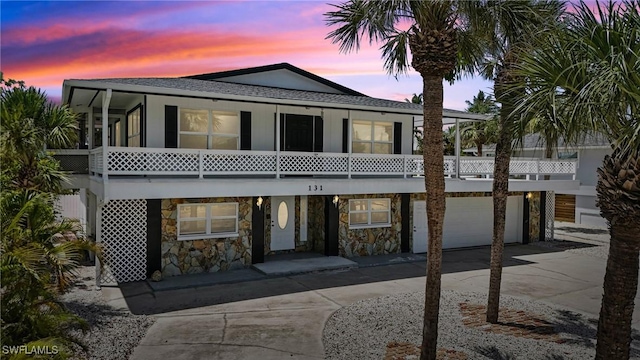 131 Bay Mar Dr, Fort Myers Beach, FL 33931 - coastal home with concrete driveway, stone siding, a garage, a shingled roof, and a sunroom