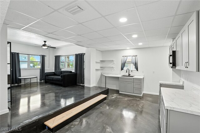 131 Bay Mar Dr, Fort Myers Beach, FL 33931 - kitchen with finished concrete floors, stainless steel microwave, gray cabinets, a drop ceiling, and ceiling fan