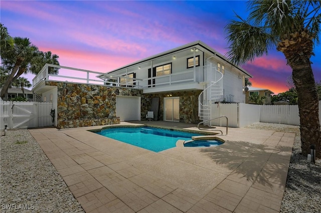 131 Bay Mar Dr, Fort Myers Beach, FL 33931 - back of property at dusk with stairs, stone siding, a patio, a gate, and a pool with connected hot tub