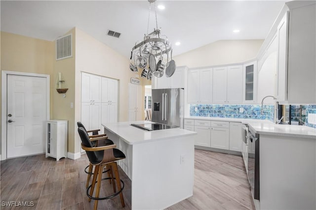 15878 Gleneagle Ct, Fort Myers, FL 33908 - kitchen with appliances with stainless steel finishes, a center island, light countertops, decorative backsplash, and lofted ceiling