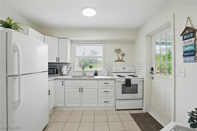 7434 Cares Away Park Cir, Bokeelia, FL 33922 - kitchen with white appliances, light tile patterned floors, backsplash, white cabinets, and light countertops