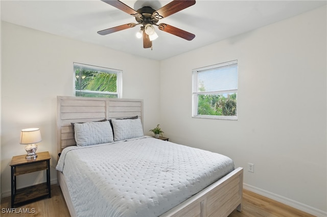 7434 Cares Away Park Cir, Bokeelia, FL 33922 - bedroom featuring multiple windows, light wood-style flooring, and ceiling fan
