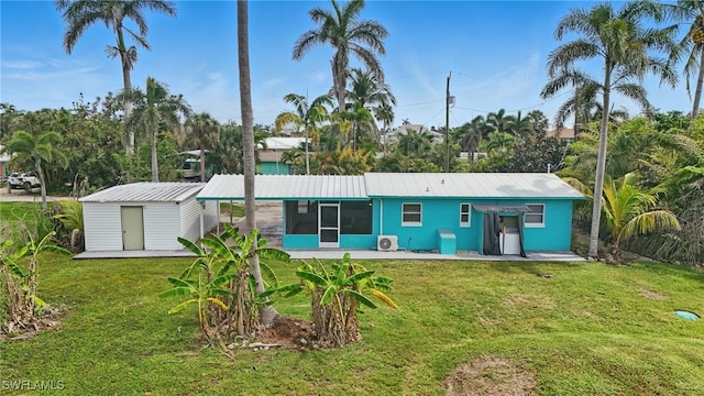 7434 Cares Away Park Cir, Bokeelia, FL 33922 - rear view of property with a sunroom, a yard, a storage unit, and a metal roof